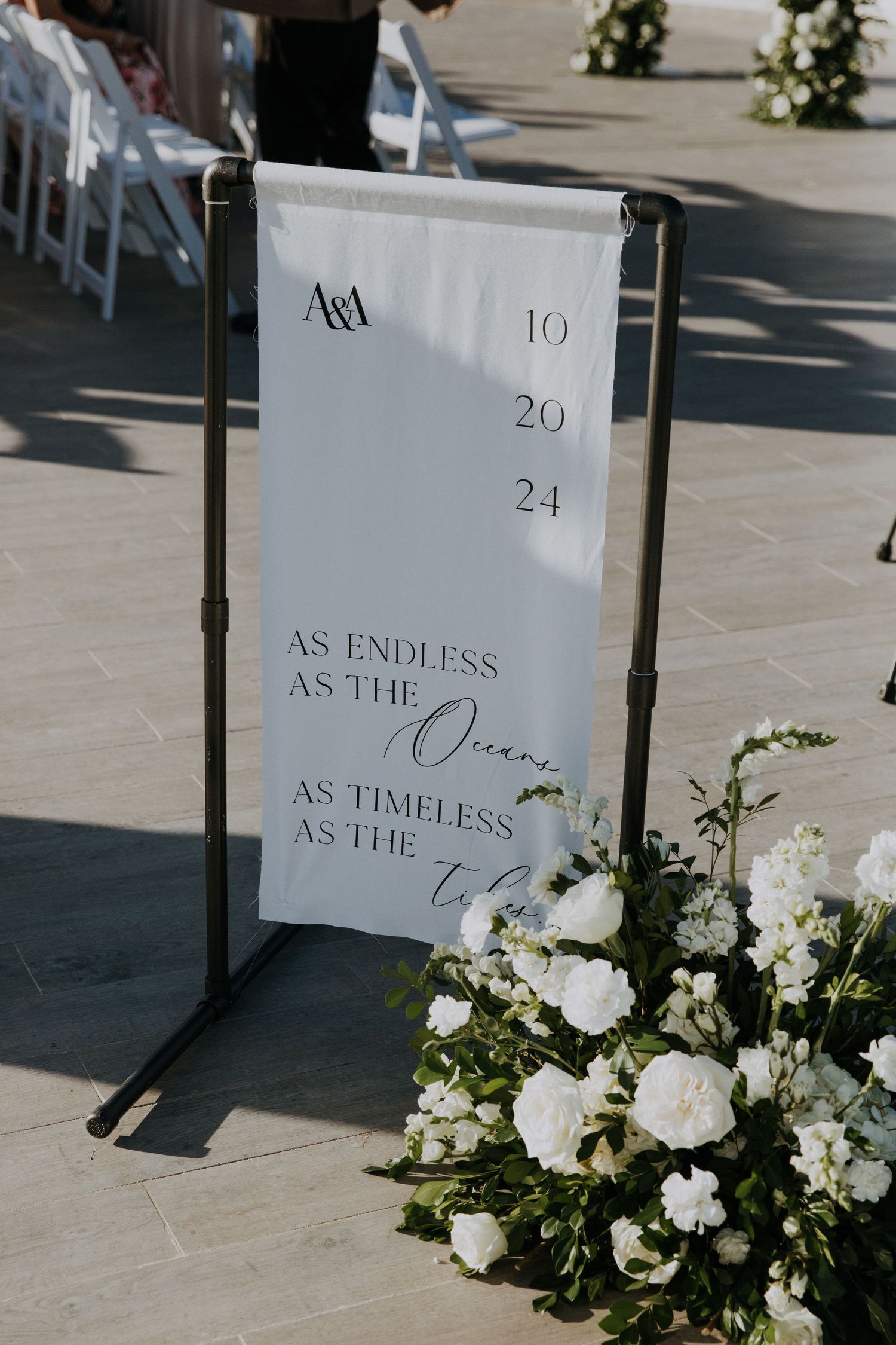 Wedding signage with date and romantic text among white floral arrangements.