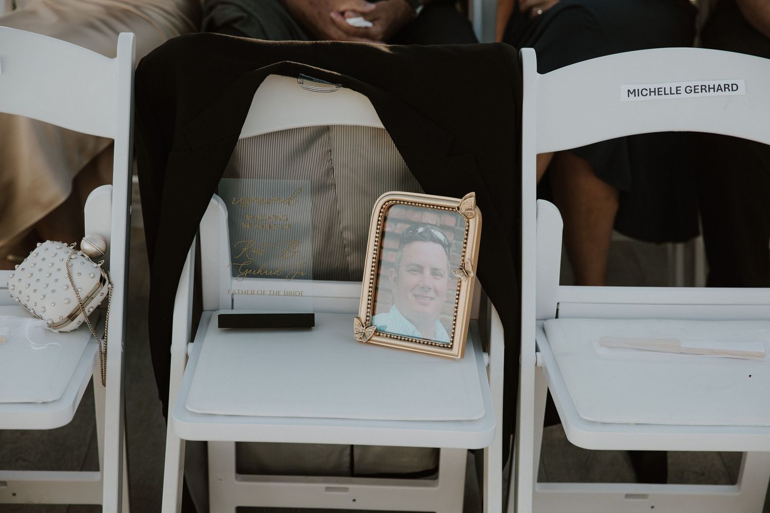 A framed photo sits on a white folding chair at what appears to be a memorial or wedding service setup.