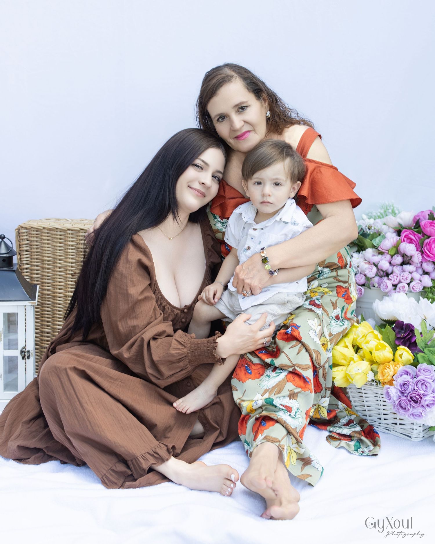 Family portrait with decorative flowers, lanterns and wicker furniture against a light backdrop.