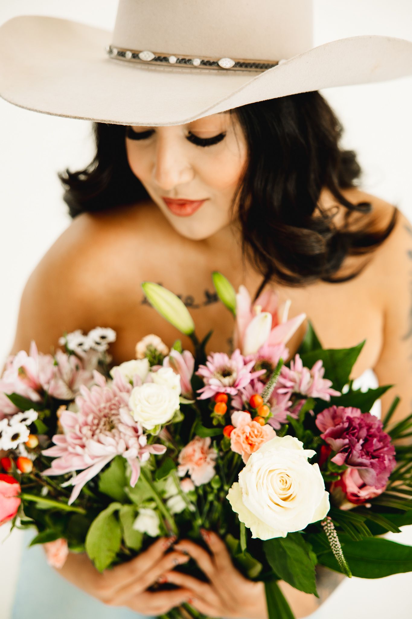 Studio birthday photoshoot of a cowgirl posing on a posing block while she celebrates with flowers in a colorado studio.