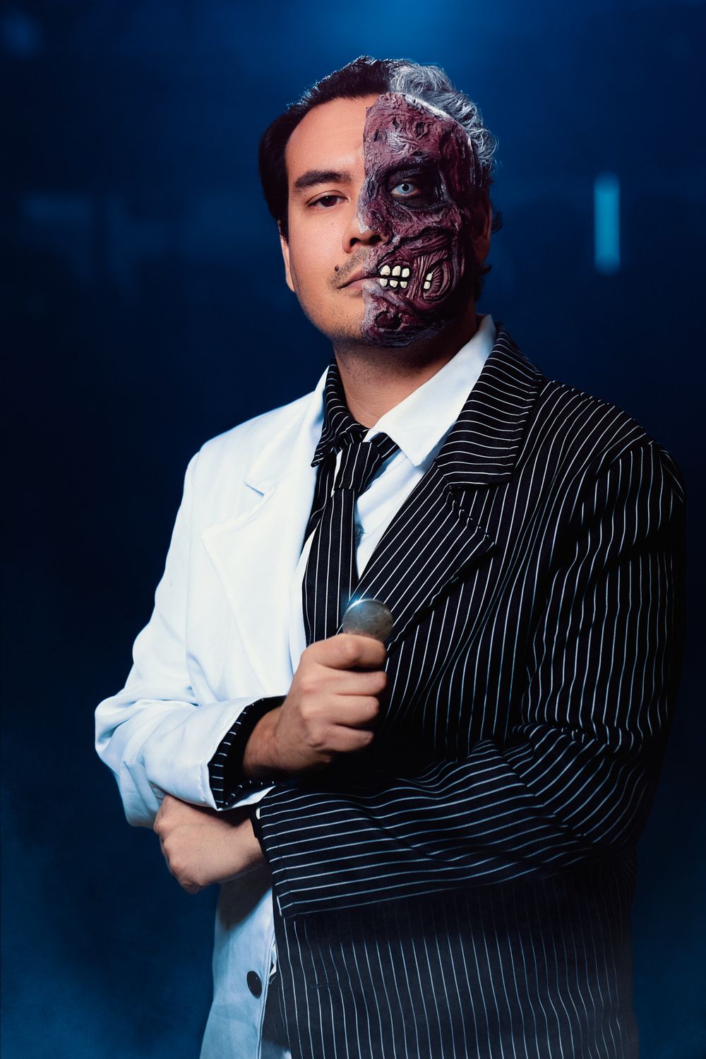 Creative split portrait with half a face normal in white suit and half transformed into dark skull makeup with pinstripe suit.