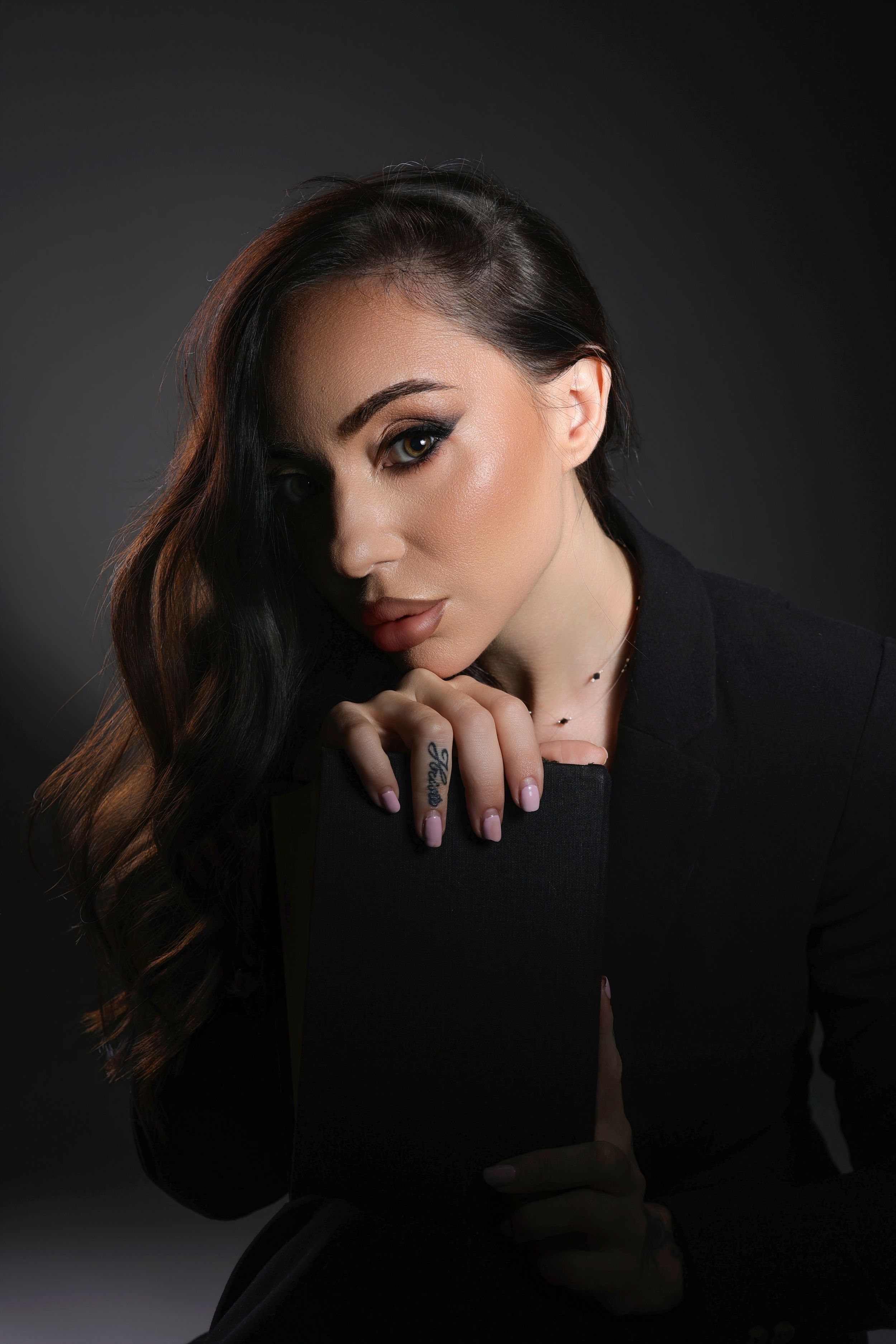 Dramatic studio portrait series showing a figure in dark clothing against black background with moody lighting and shadows.