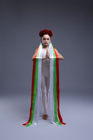 Artistic performance with tricolor striped fabric creating vertical lines against gray background.