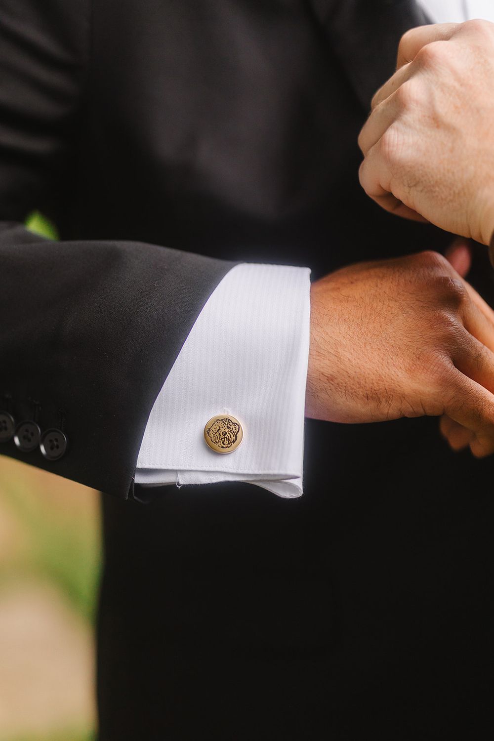 Close-up of formal black suit sleeve with white french cuff and decorative gold cufflink.
