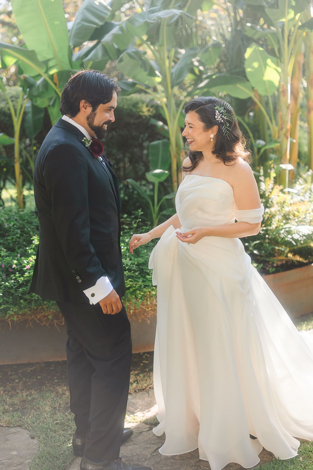 Romantic first look moment between couple in wedding attire surrounded by lush tropical garden setting.