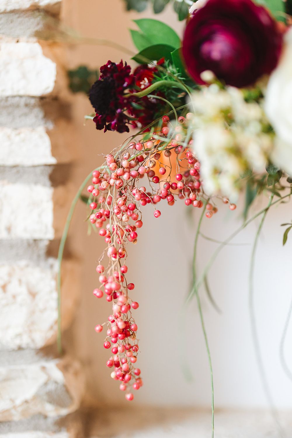 Pink currant flowers cascade elegantly from white vases against a soft neutral background with burgundy floral accents.