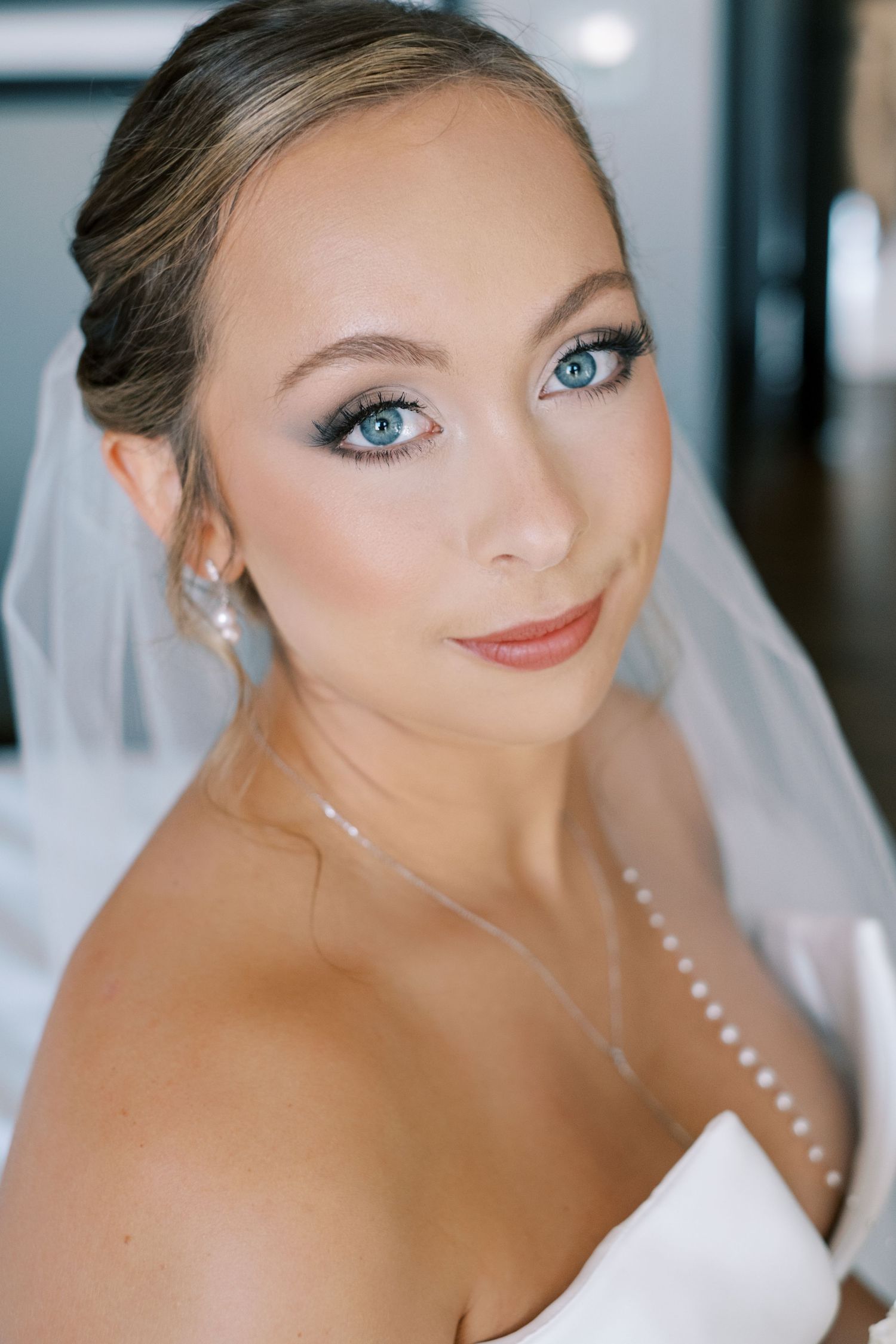 A bride with dramatic eye makeup and a pearl necklace poses in a classic close-up portrait series.