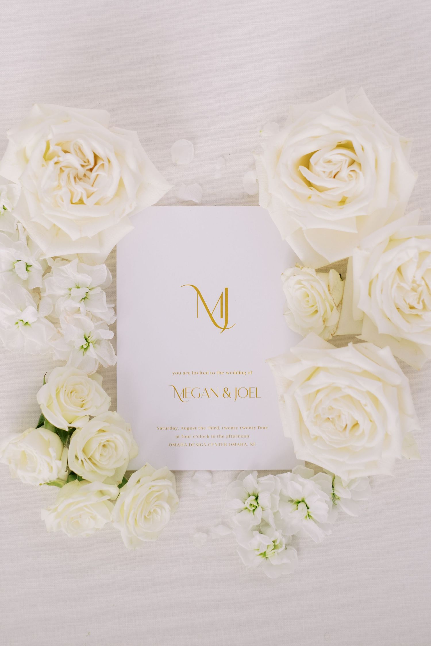 Elegant white wedding invitation cards surrounded by fresh white roses.