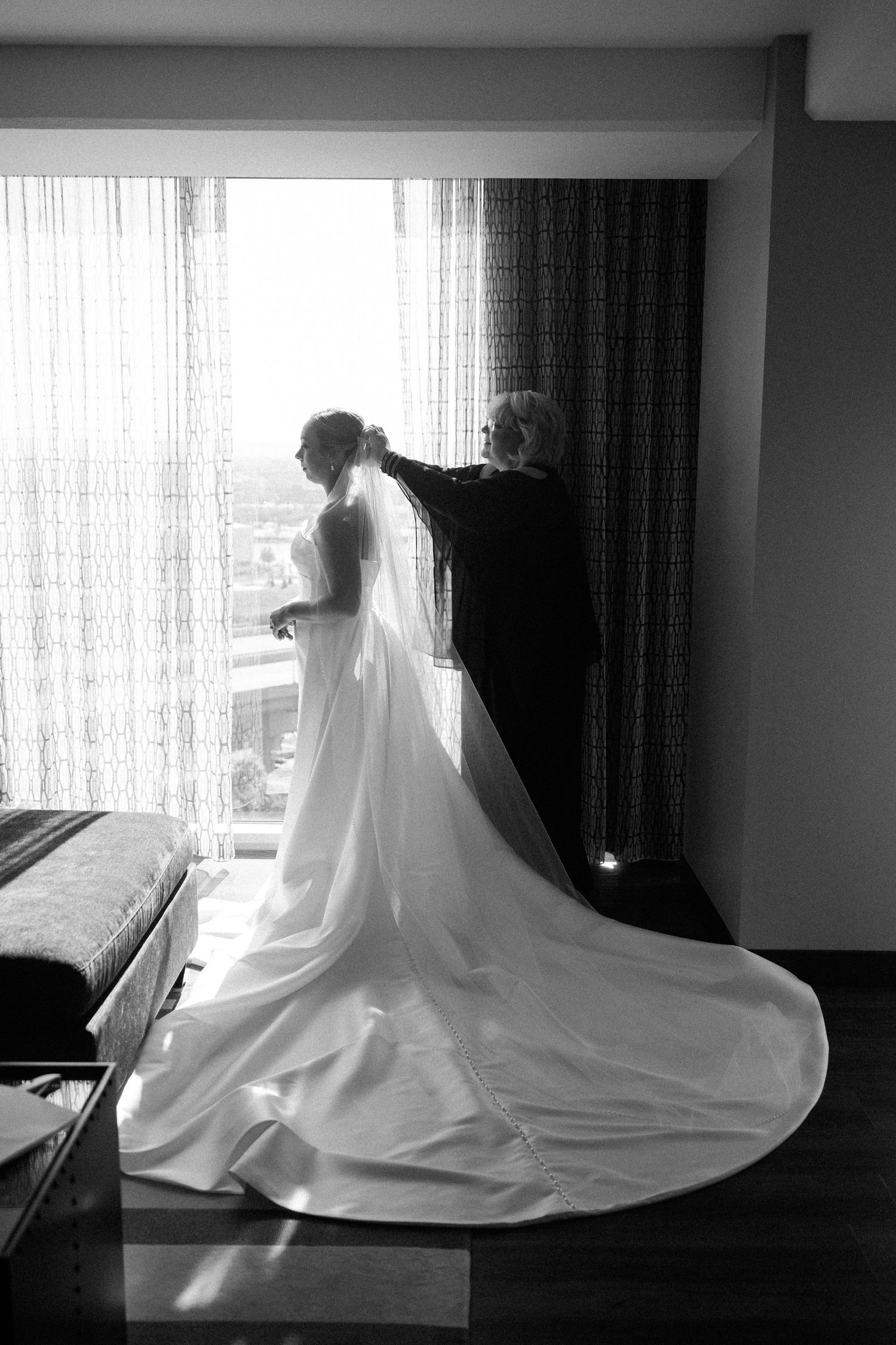 A dramatic black and white series of wedding dress silhouettes against window light creating ethereal movement.