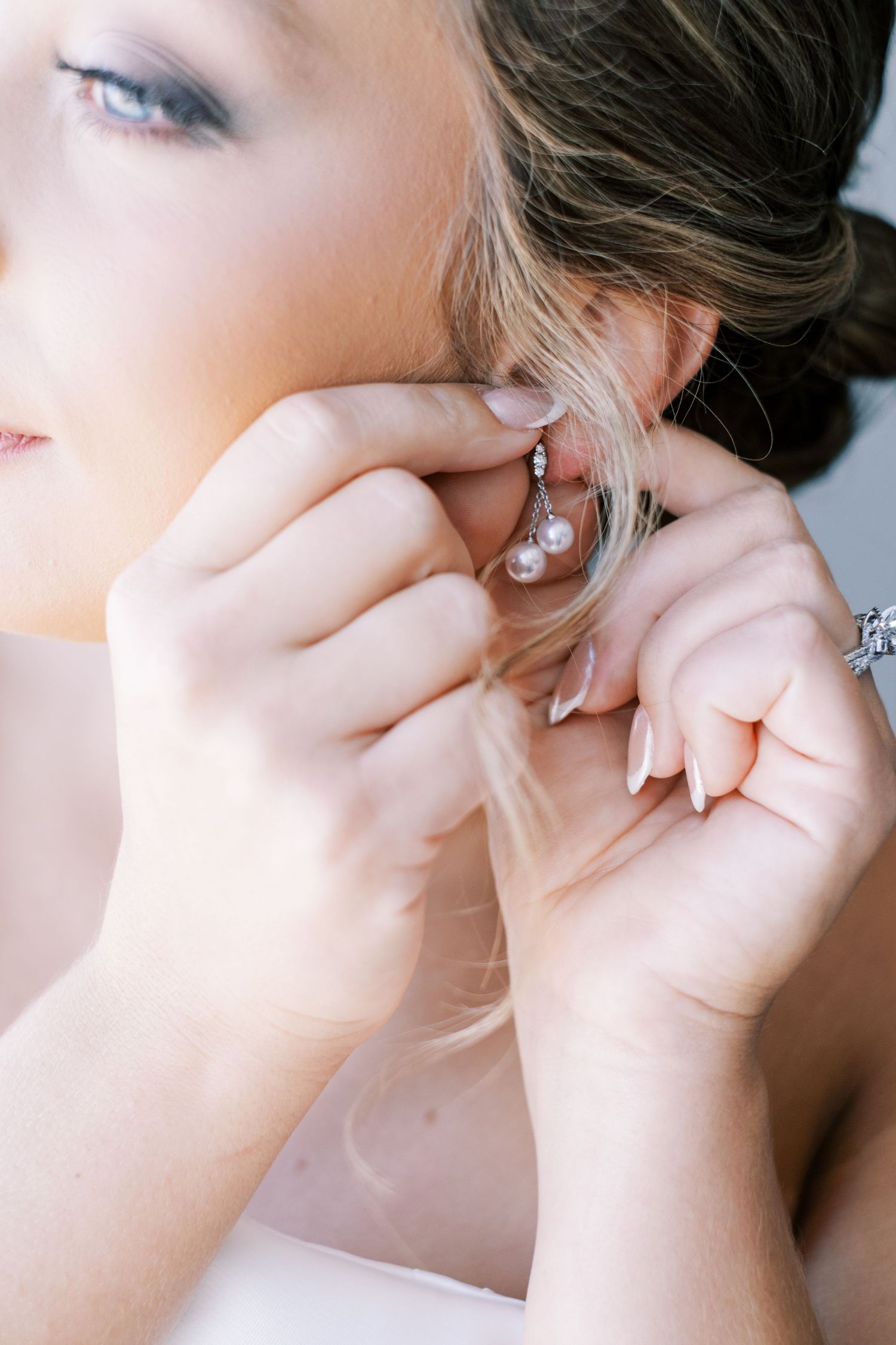 Close-up sequence showing delicate pearl earrings being put on during wedding preparations.