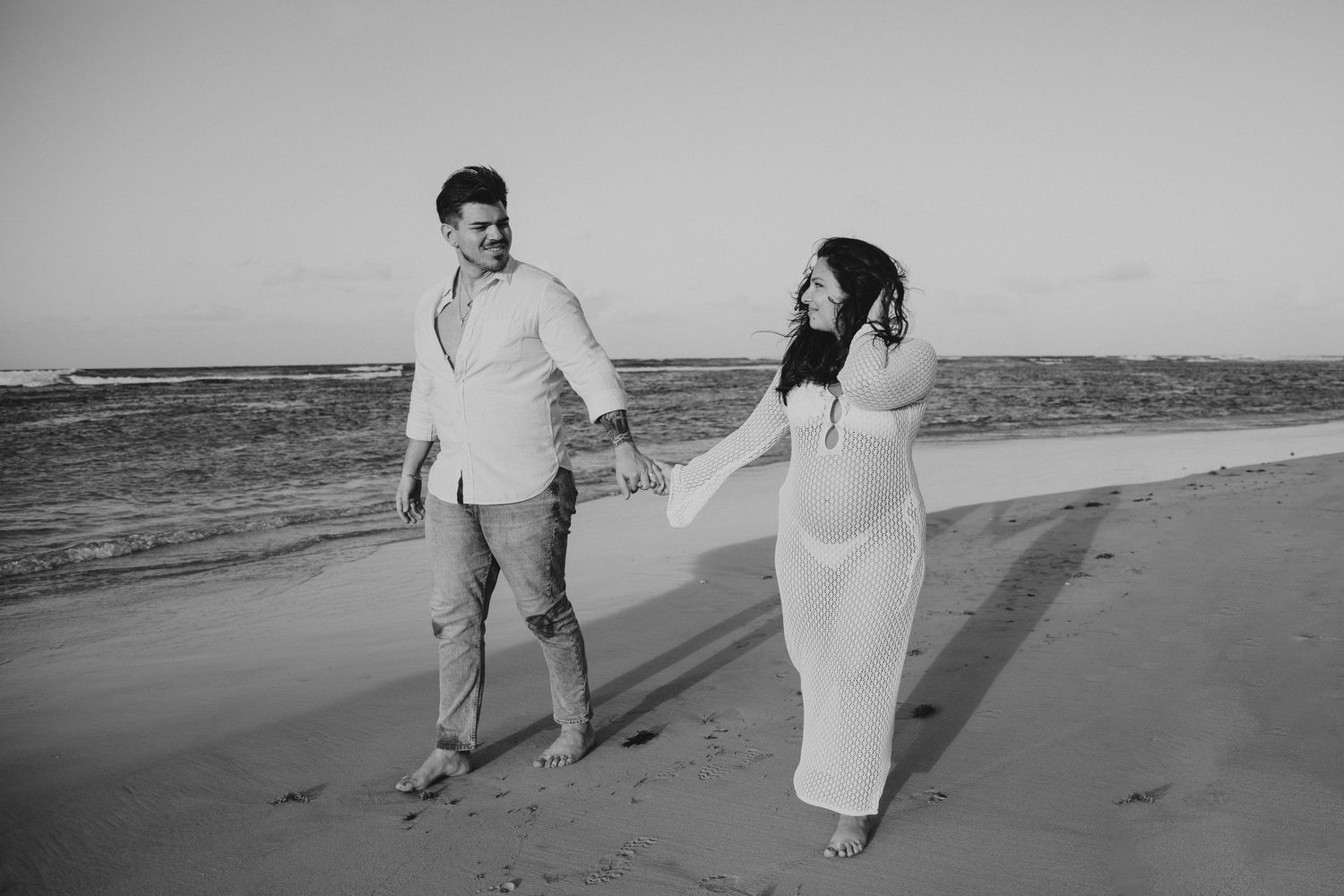 Black and white beach portraits showing couple's candid moments.