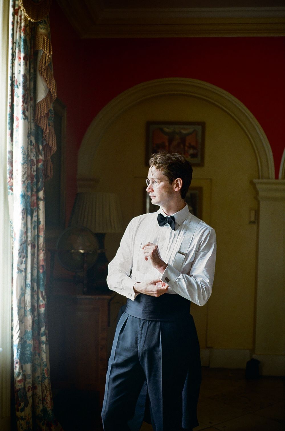 Groom adjusting cuffs set in a classic english manor house living room