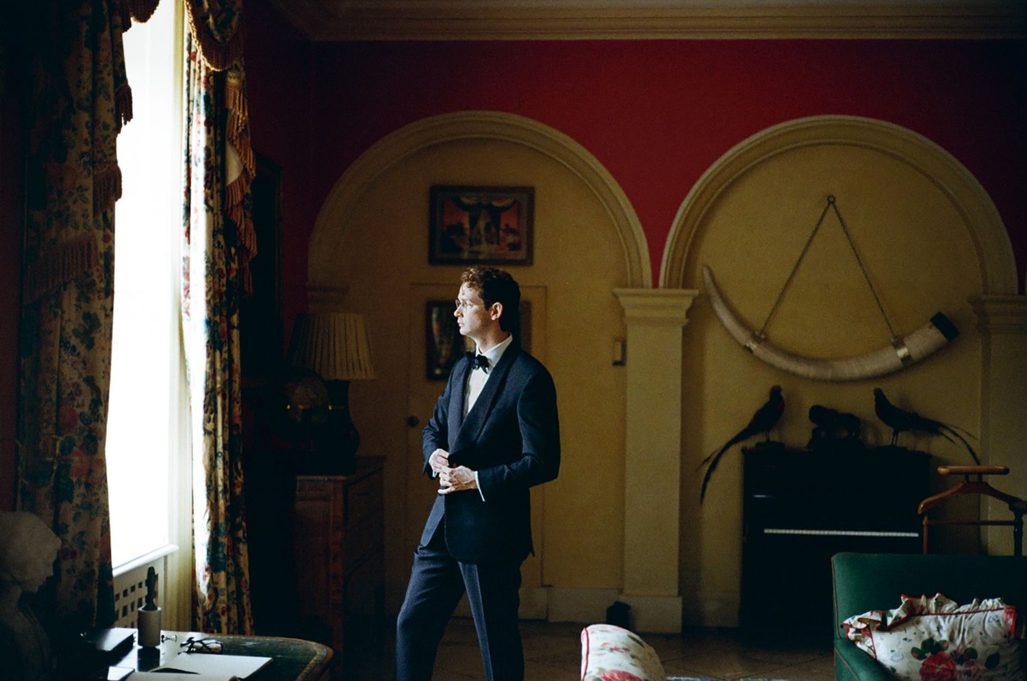 Groom adjusting blazer set in a classic english manor house living room