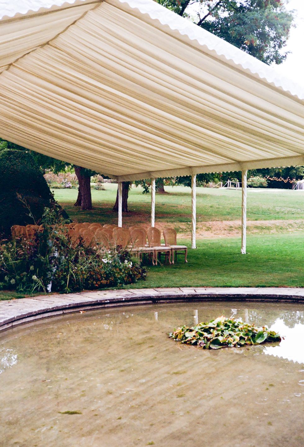 Wedding ceremony details including chairs and floral decorations underneath a tent