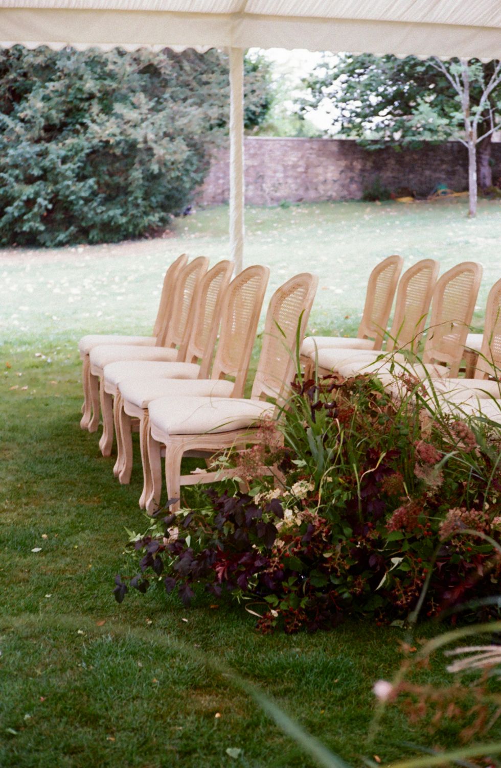 Wedding ceremony details including chairs and floral decorations underneath a tent
