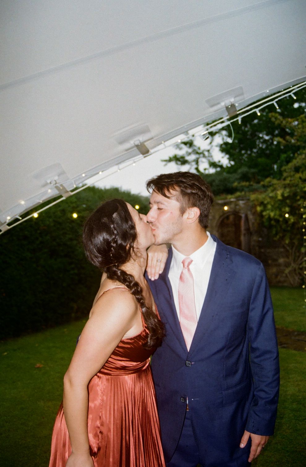 Couple sharing a kiss under a wedding tent, documentary wedding