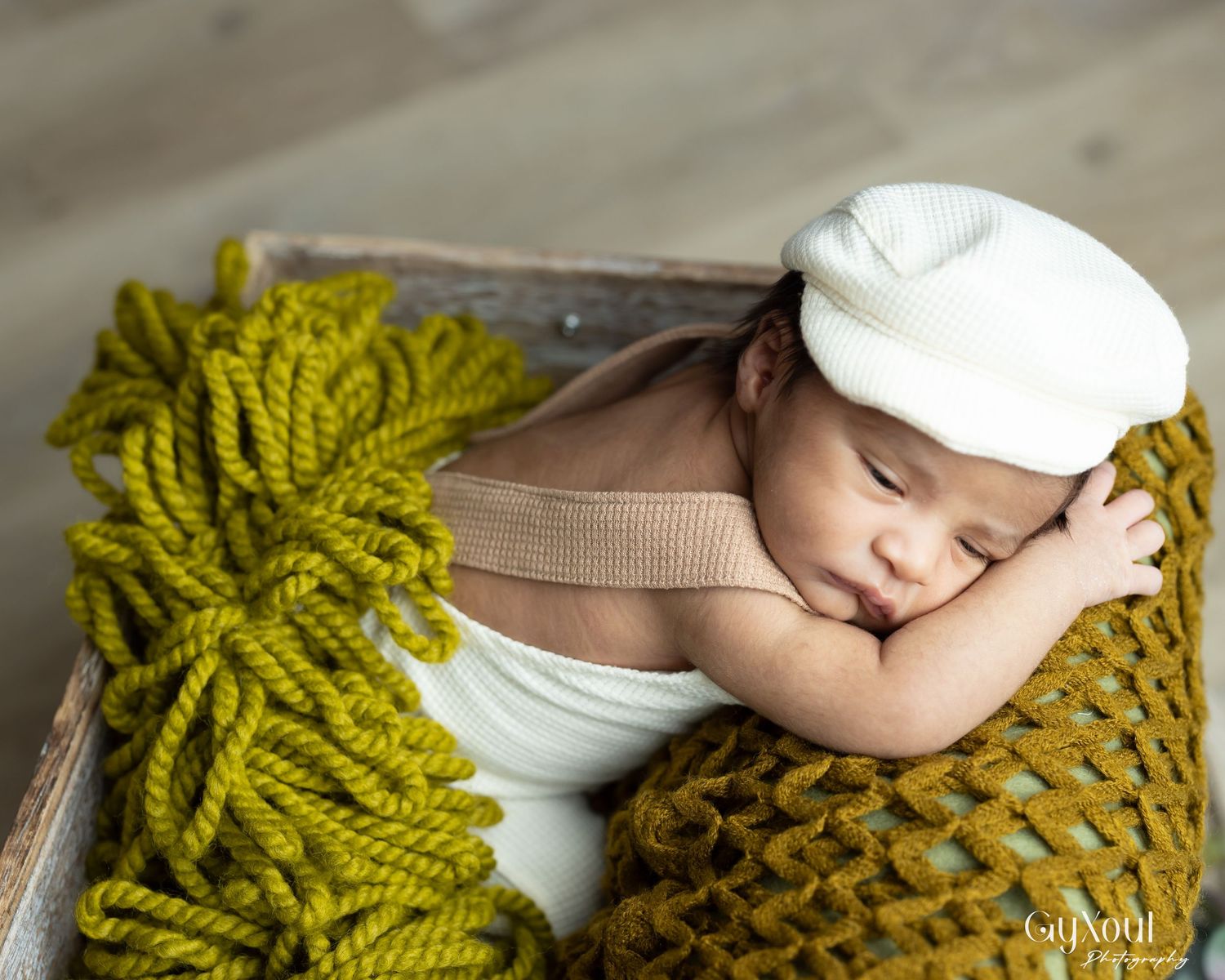 Newborn baby sleeping on soft olive green knit blanket during professional photography session.