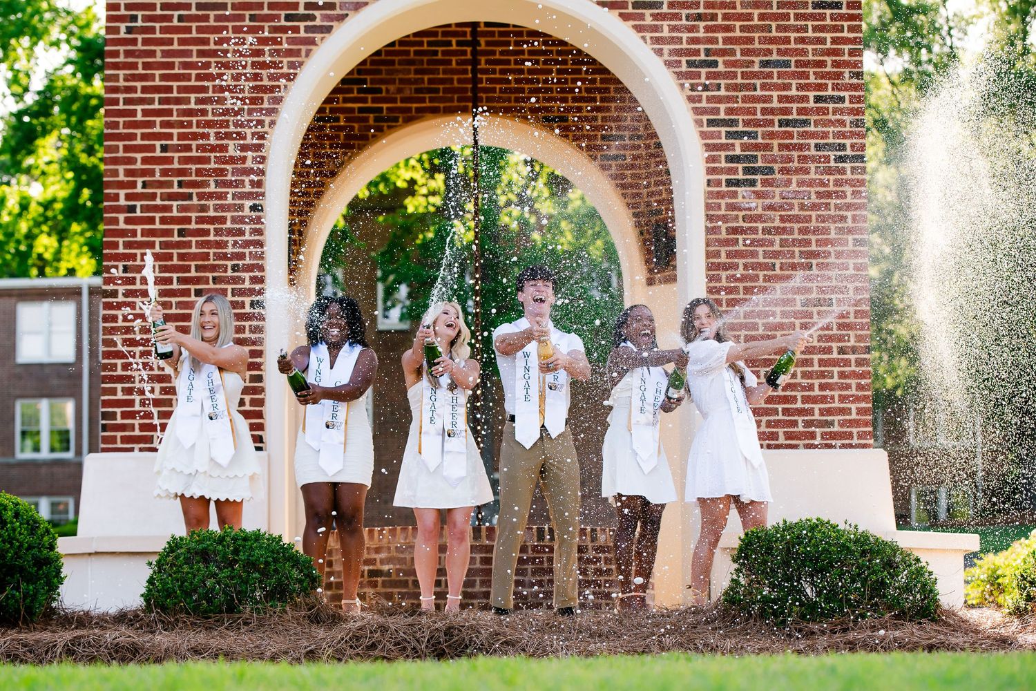 Group gathered under a brick archway on a sunny summer day.