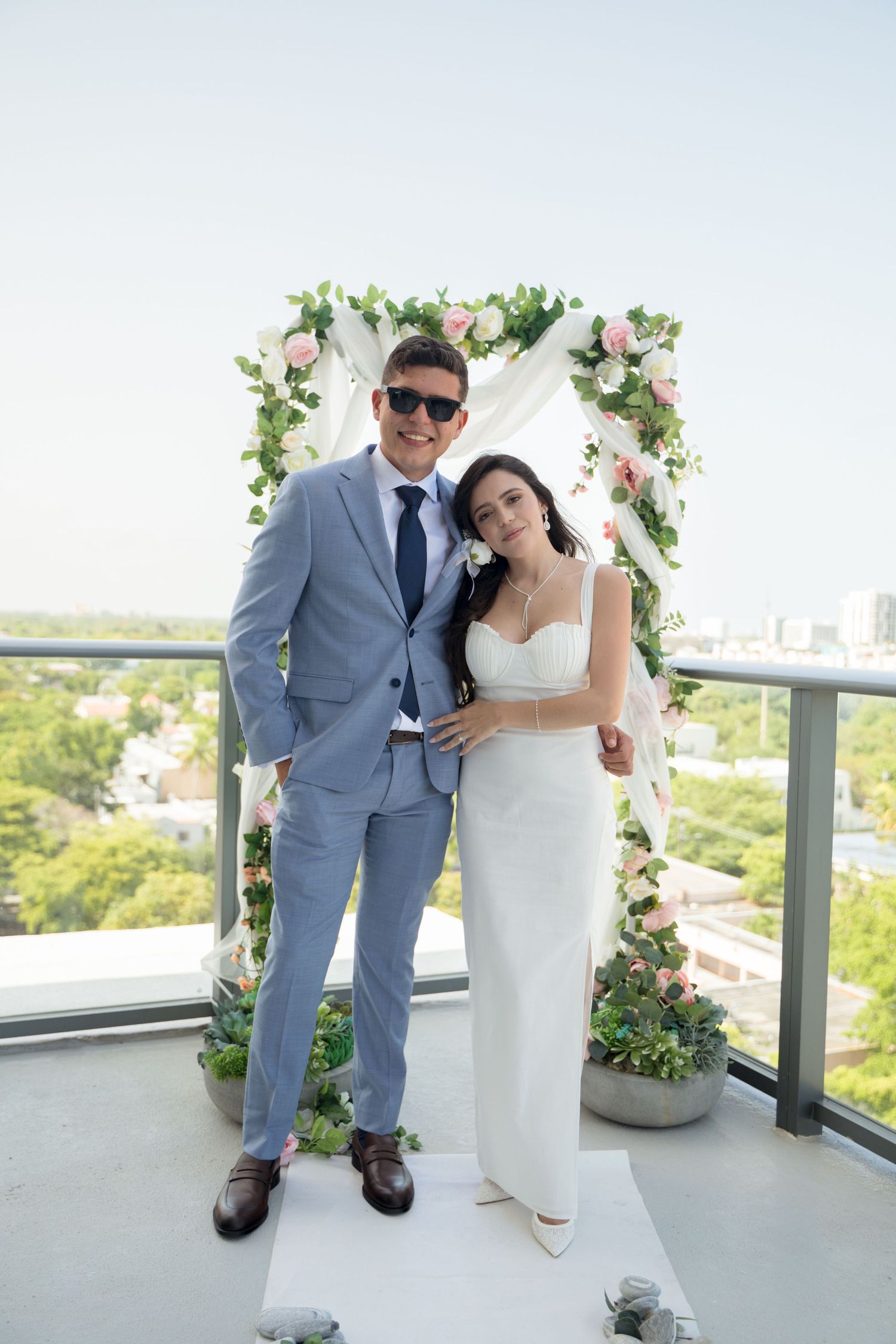 Couple shares romantic moments on a balcony with floral decorations during their rooftop wedding celebration.