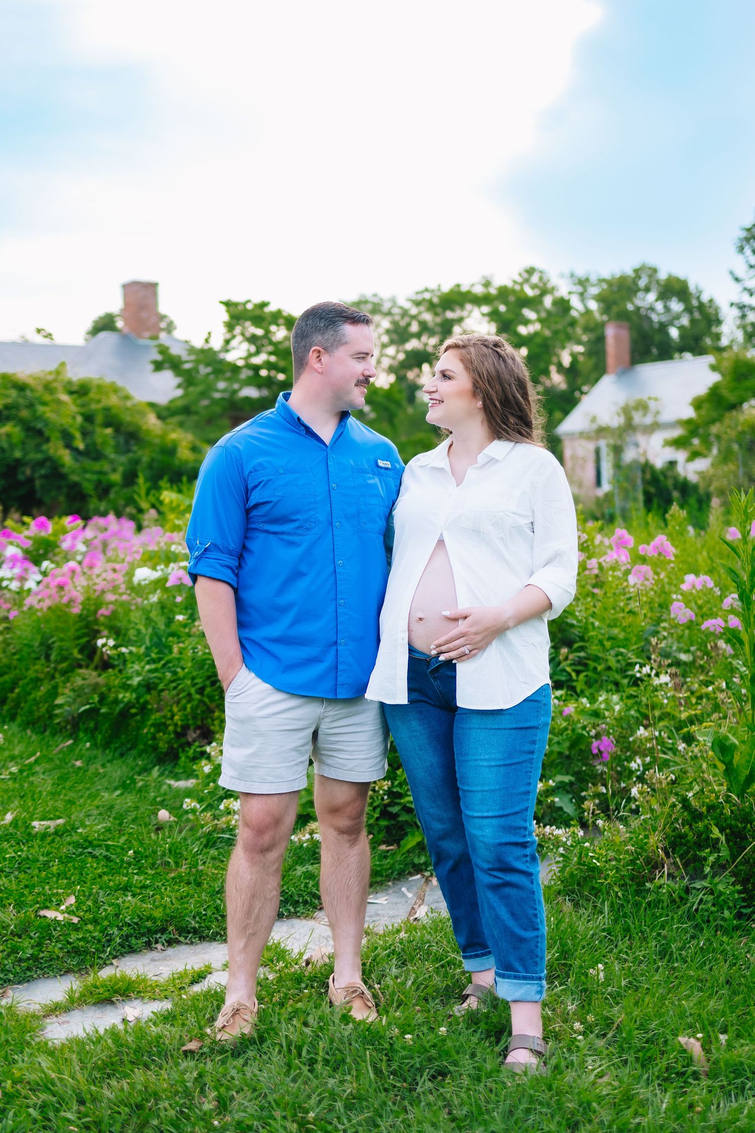 Couple sitting together in a garden with blooming pink flowers on a sunny day.