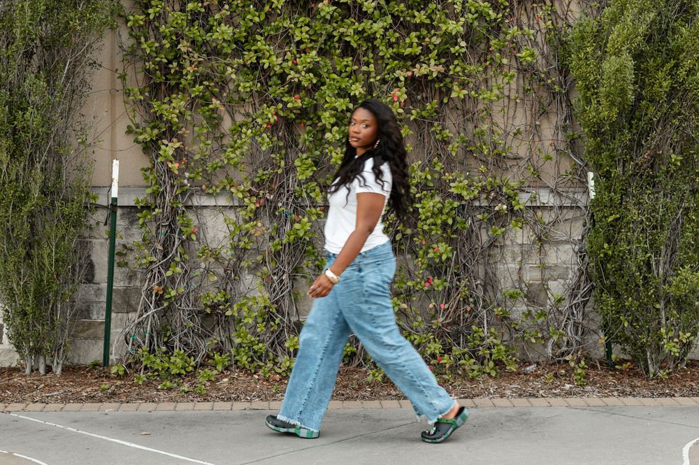 Person walking outdoors on stone path wearing flared jeans and casual shoes.