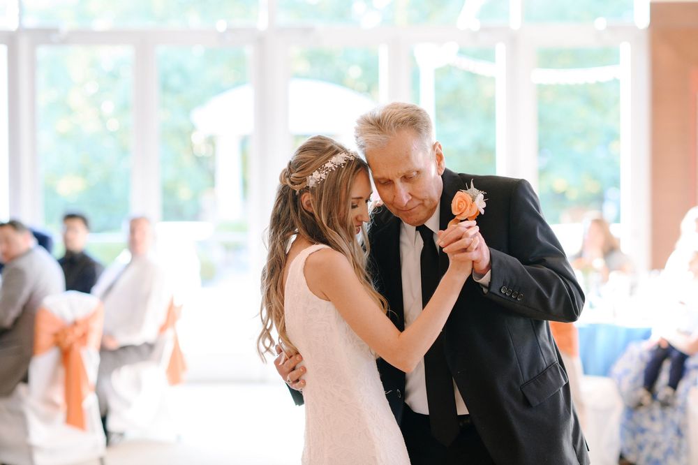 A wedding couple shares an intimate dance together during their reception celebration at an indoor venue.