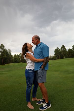 Loving couple gazing into each other eyes while embracing on a green golf course outdoors.