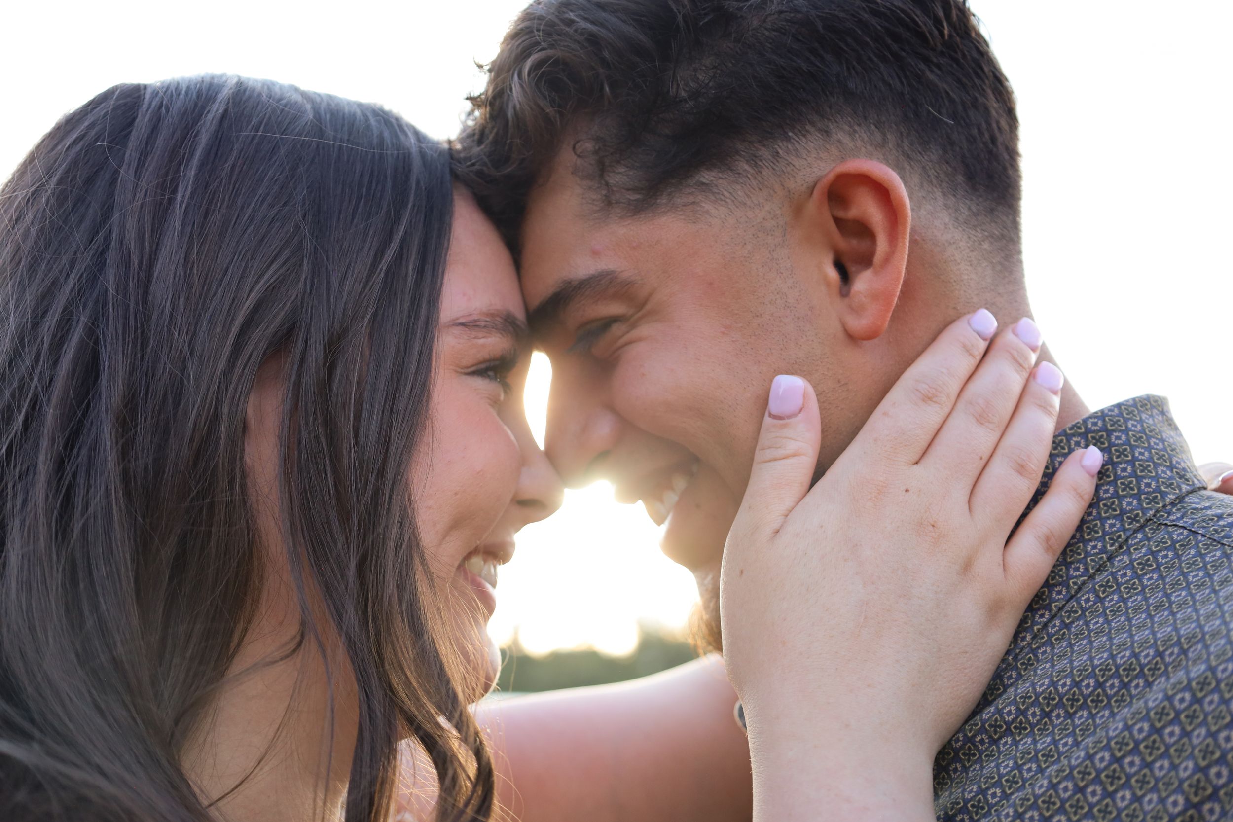 A close romantic couple touches foreheads in a tender golden sunset moment together.