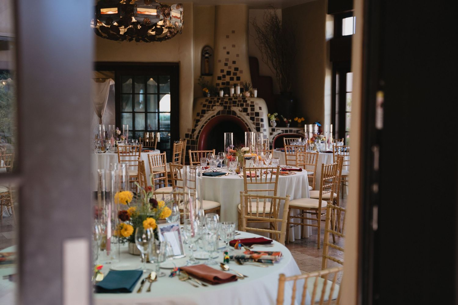 Elegant wedding reception hall with gold chiavari chairs, white tablecloths, and colorful floral centerpieces.LGBT documentary photographer