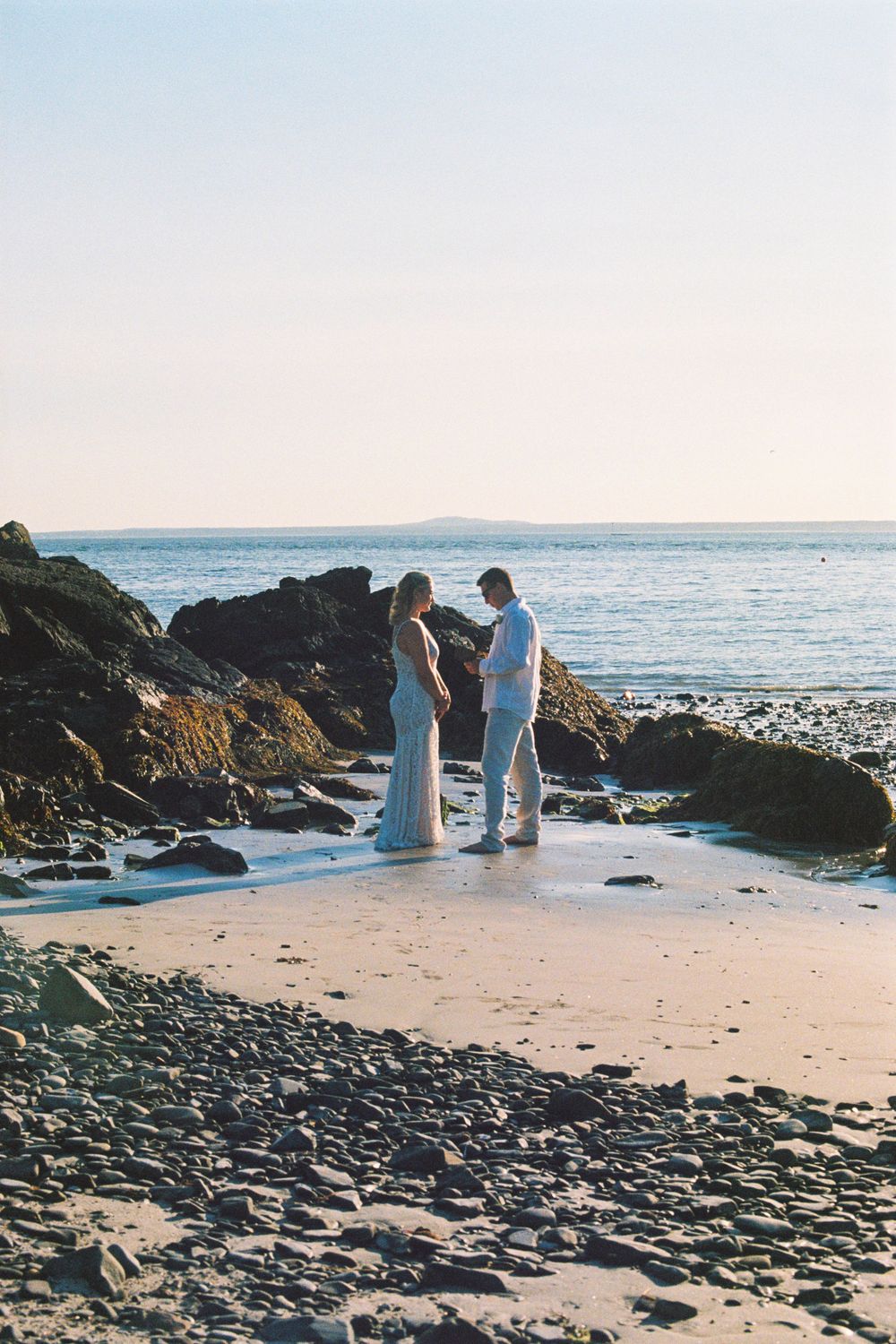 Bride and groom read their vows to each other privately with bare feet on the beach after their intimate ceremony on analog film.