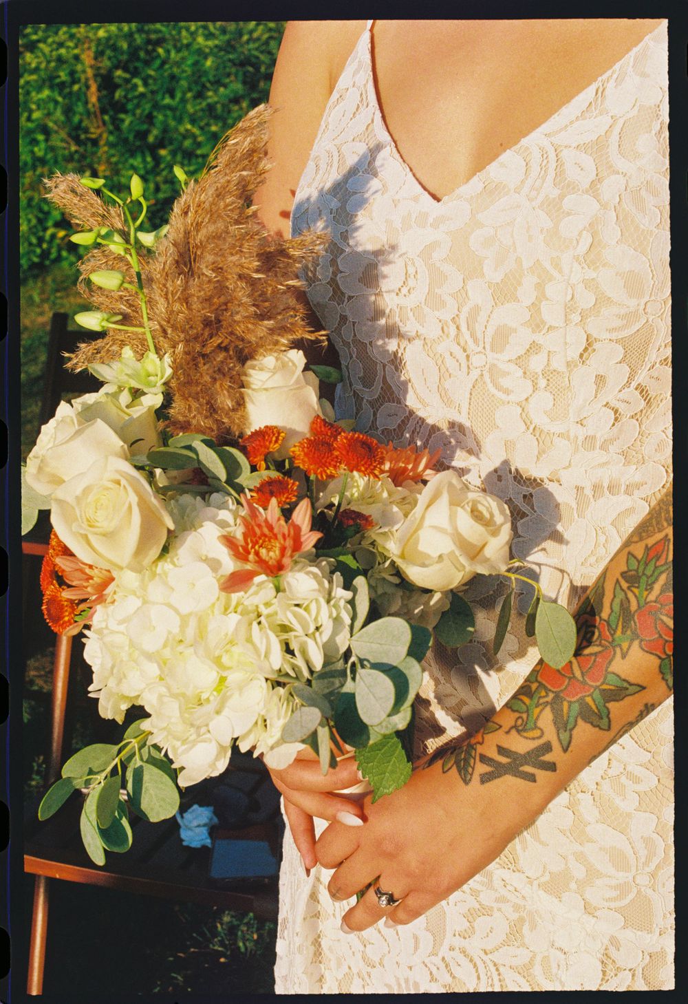 A detail image on film of the bride in a white lace dress holds her floral bouquet close in Kennebunkport, Maine.