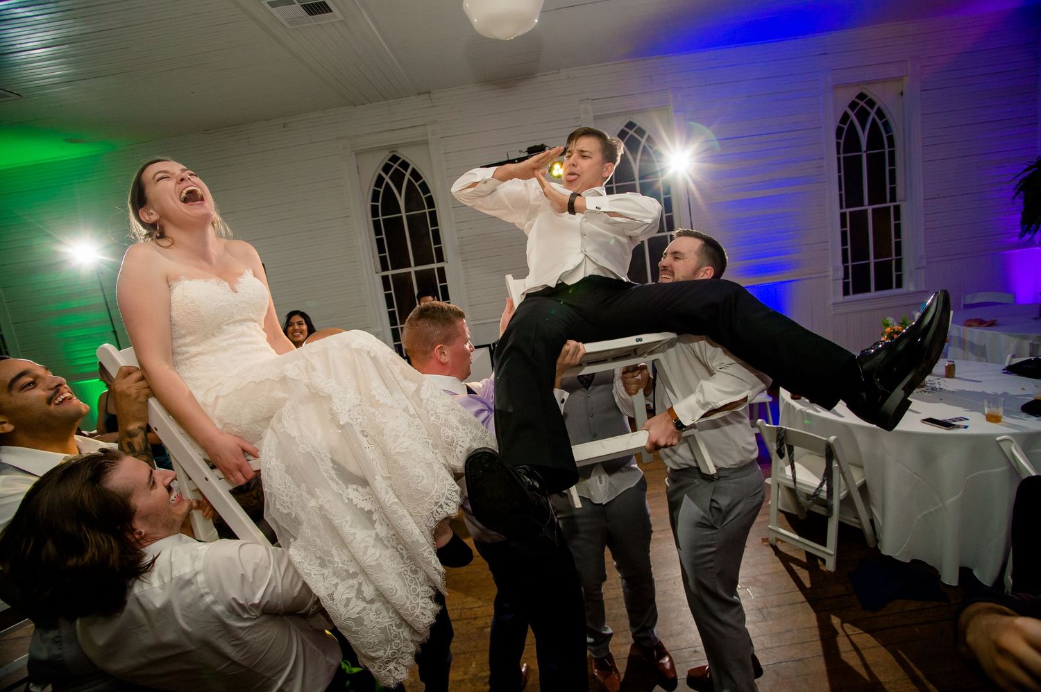 Wedding reception guests dance on the dance floor while a bride in white dress spins and twirls with the crowd.