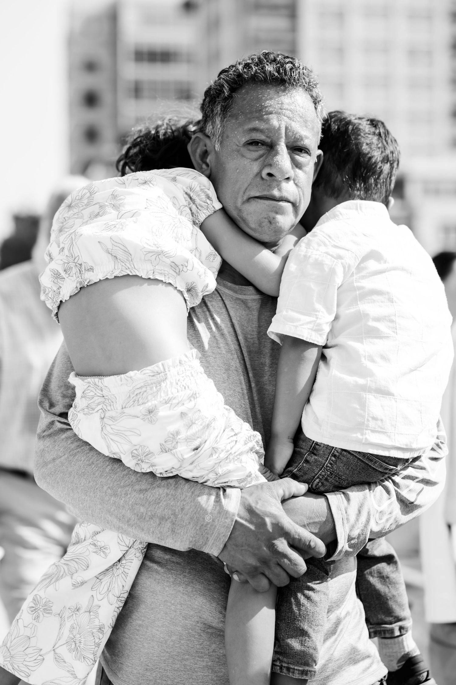 A heartwarming black and white photo showing an elderly person holding two young children in an embrace.