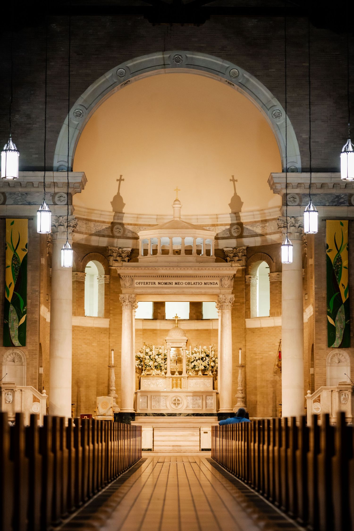 Interior of a church with illuminated pews leading to an ornate altar under a grand archway.