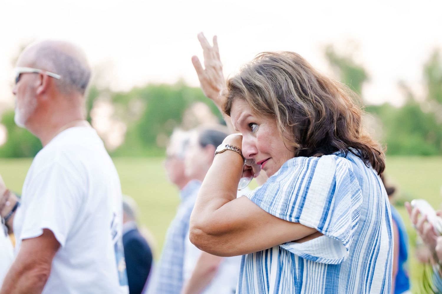 People gathering outdoors during a religious event with emotional expressions.