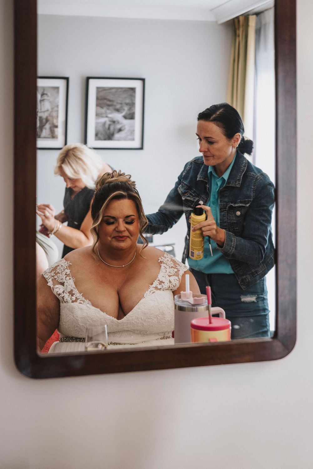 A person wearing a lace wedding dress getting ready in front of three mirrors during wedding preparations.