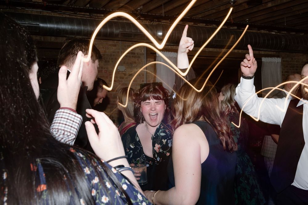 Group of people dancing at a lively party with light painting streaks in the background.