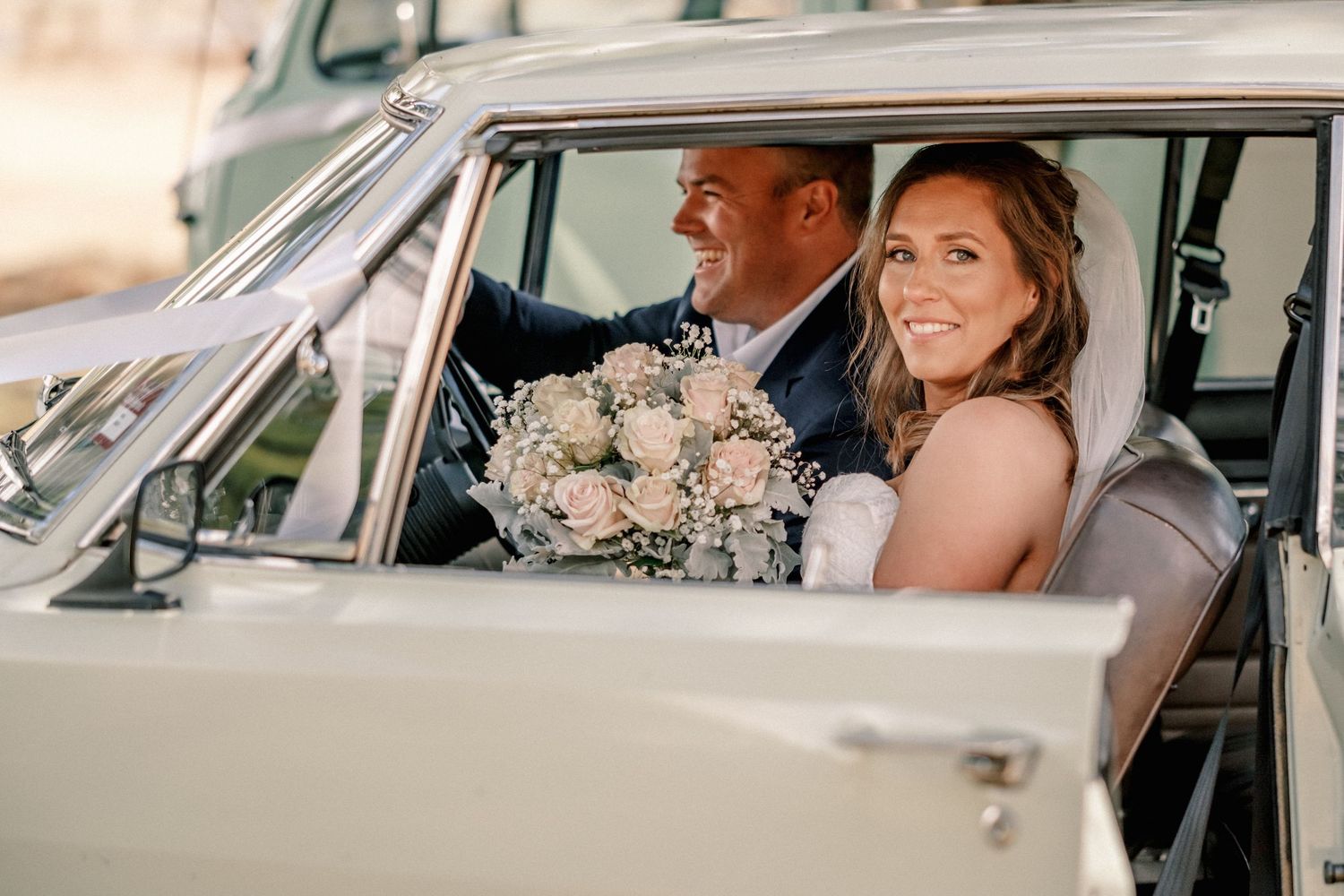 Elegant wedding couple poses in and around vintage cars during their special day.