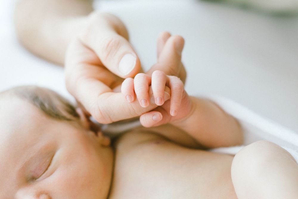 Close-up of tiny baby hands and delicate fingers against white background.