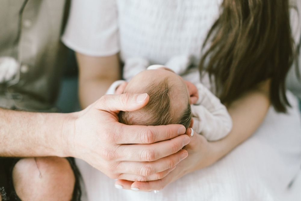Close-up details of tender family moments during newborn photo session with dog.