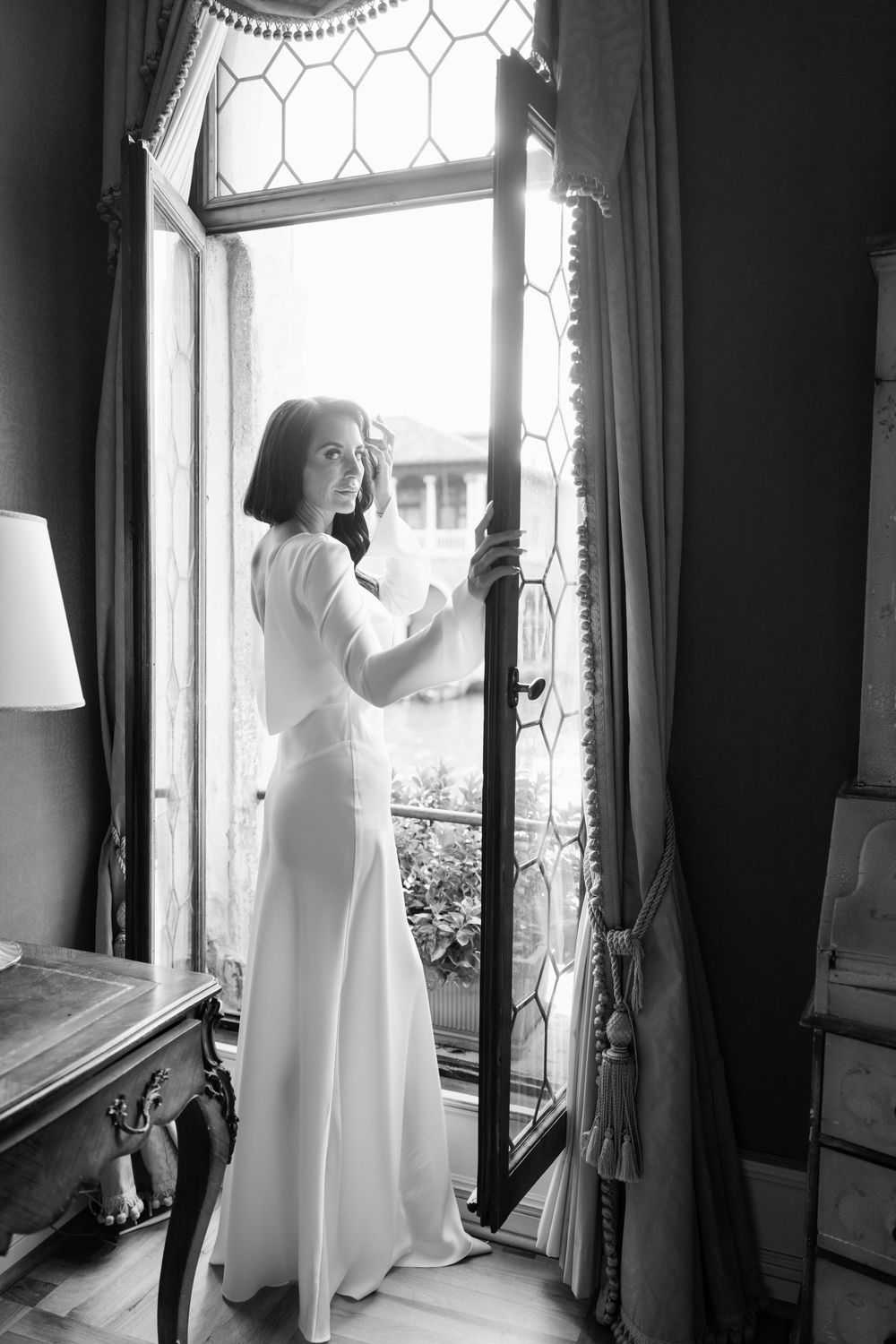 A series of black and white photographs showing a figure in a white dress standing by a window with decorative glass.