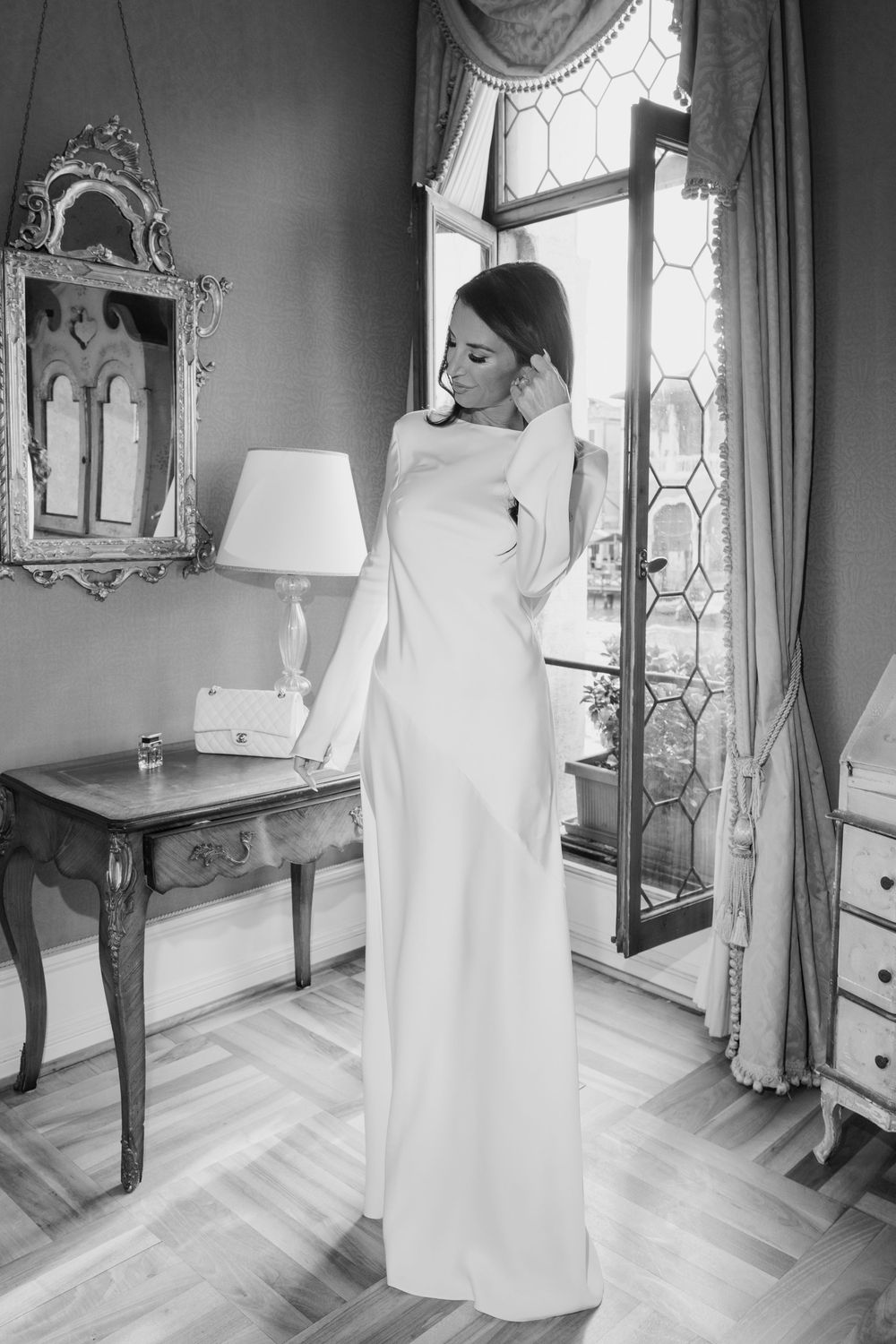 Black and white collage of a bride in a wedding dress getting ready in an elegant room with ornate mirrors and furniture.