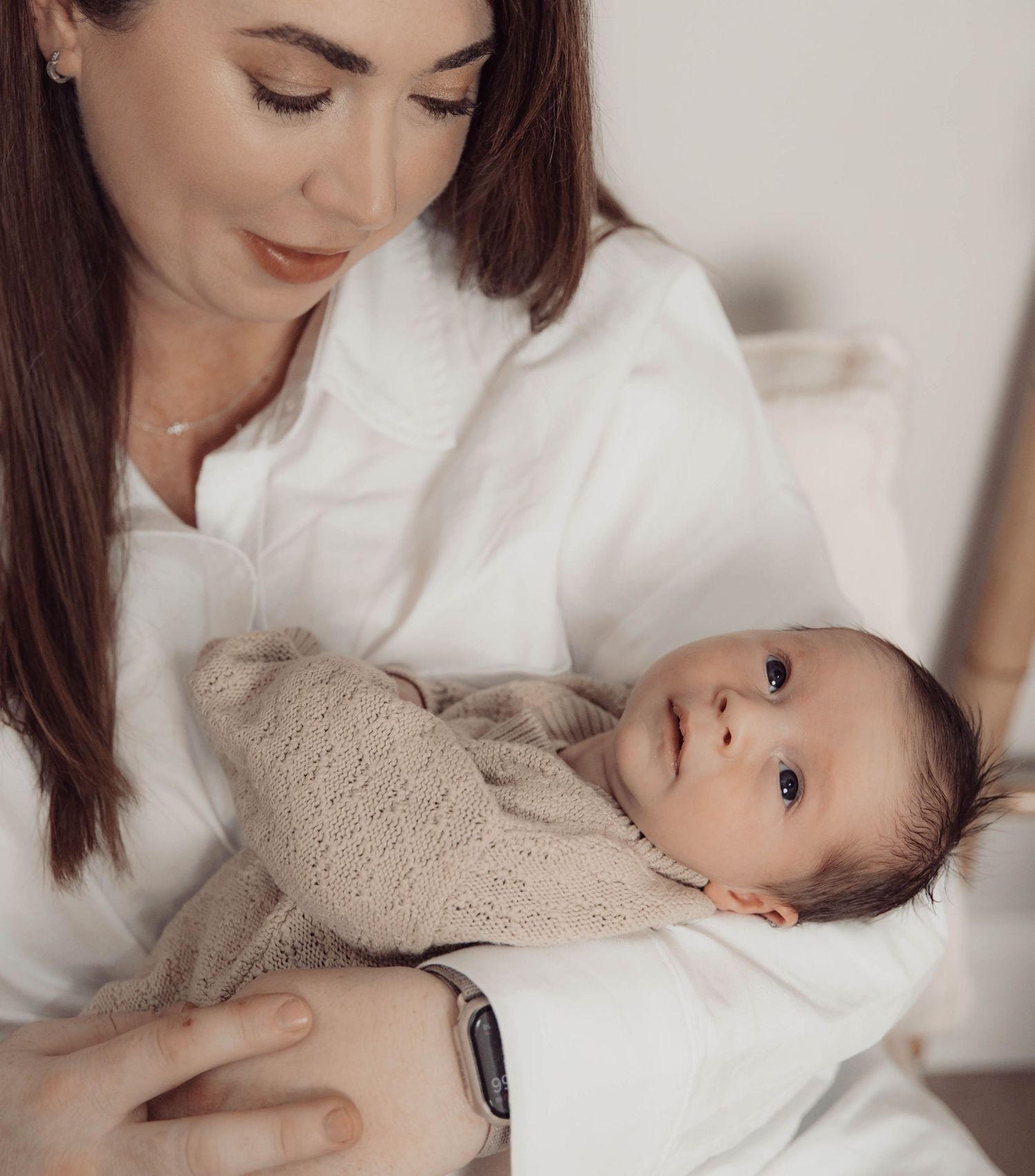 Tender moment between parent and baby in white room.