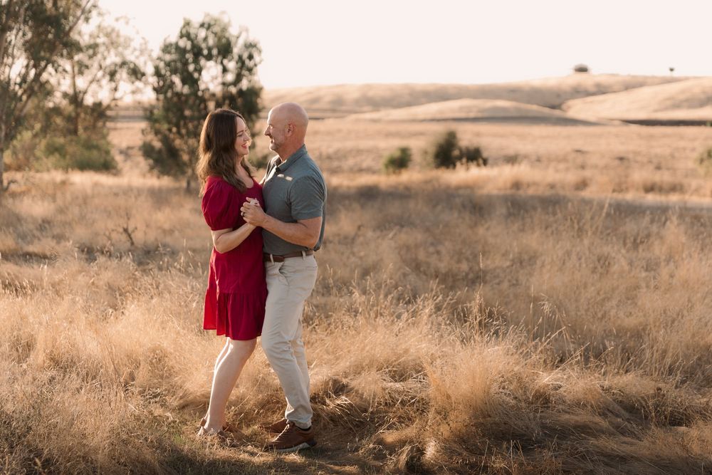 Family embraces on dirt path during golden hour in foothill landscape at Tesoro Viejo.