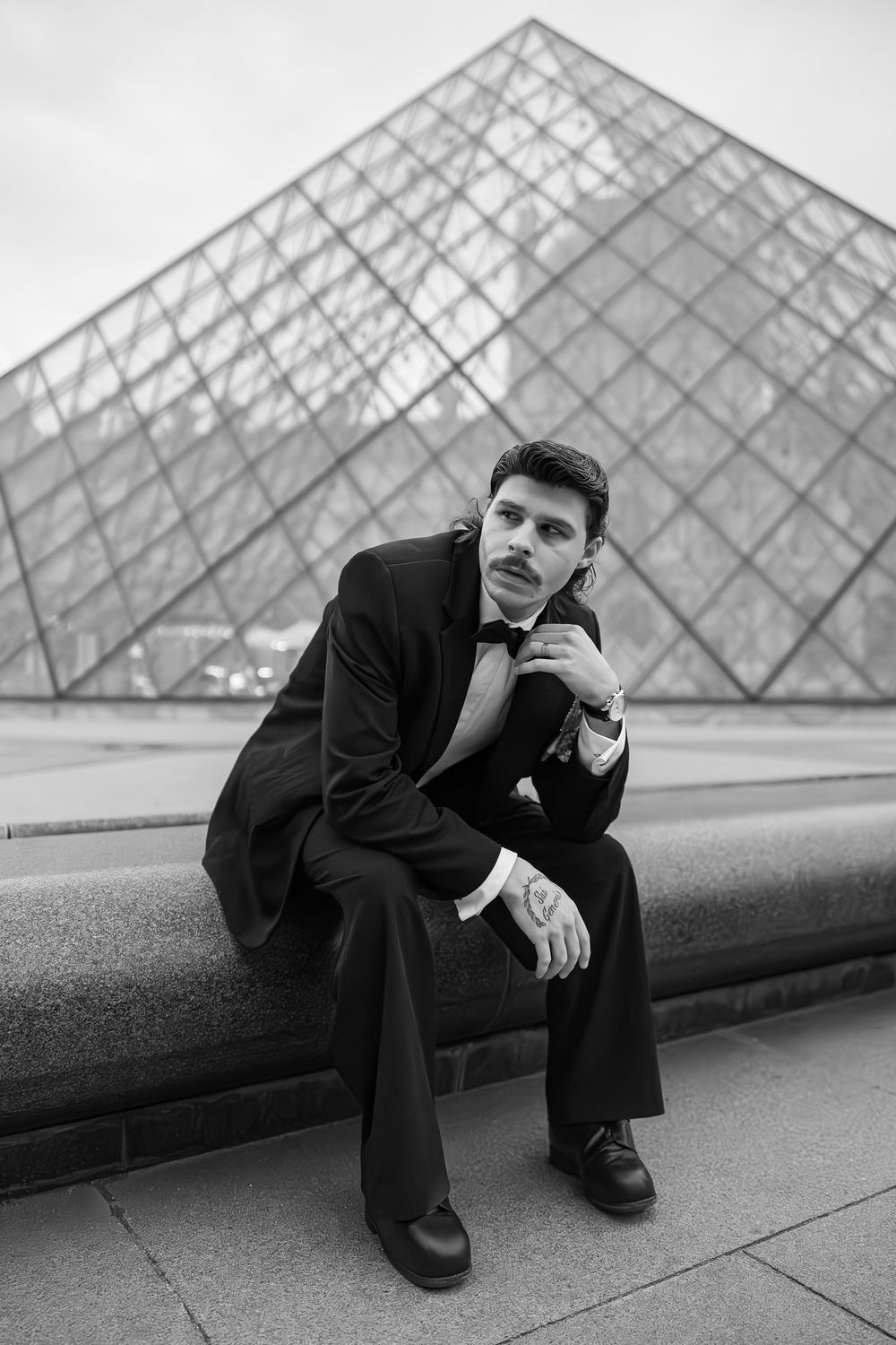Black and white portrait series against geometric glass pyramid architecture.