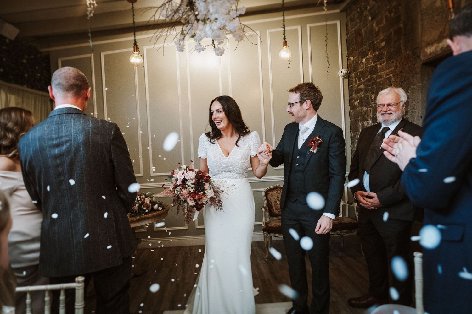 Joyful wedding celebration with guests blowing bubbles as couple walks through during reception.