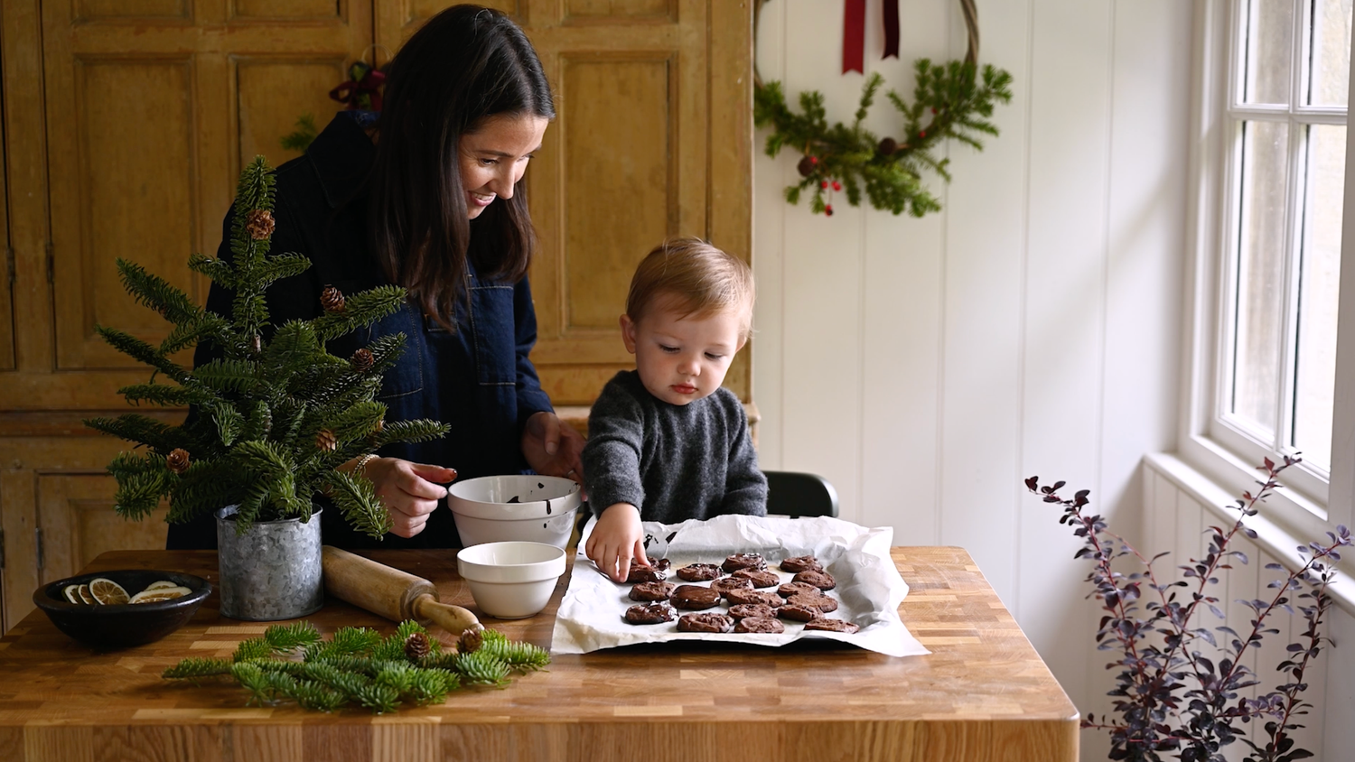 Woman bakes chocolate biscuits with little boy at Christmas time