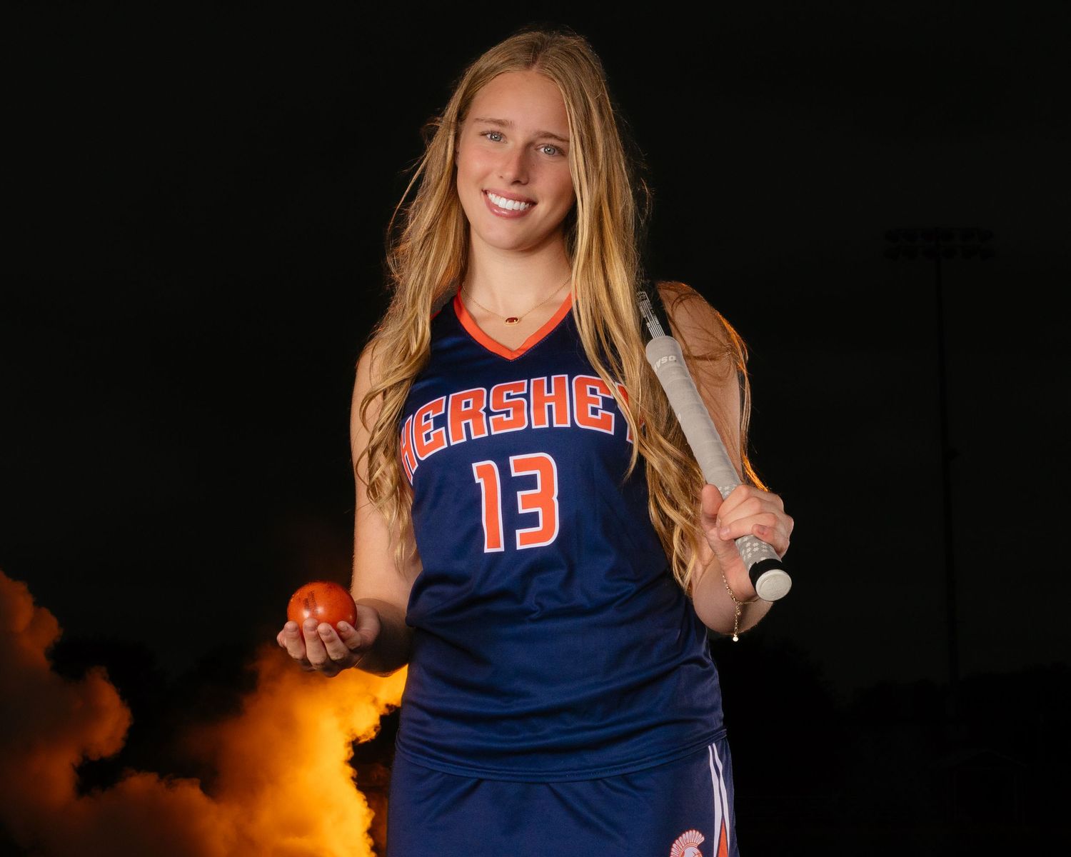 Hershey Trojans field hockey player Media Day portrait with orange smoke and stick, by Deanna Fox, SportsFox Photography, Hershey PA