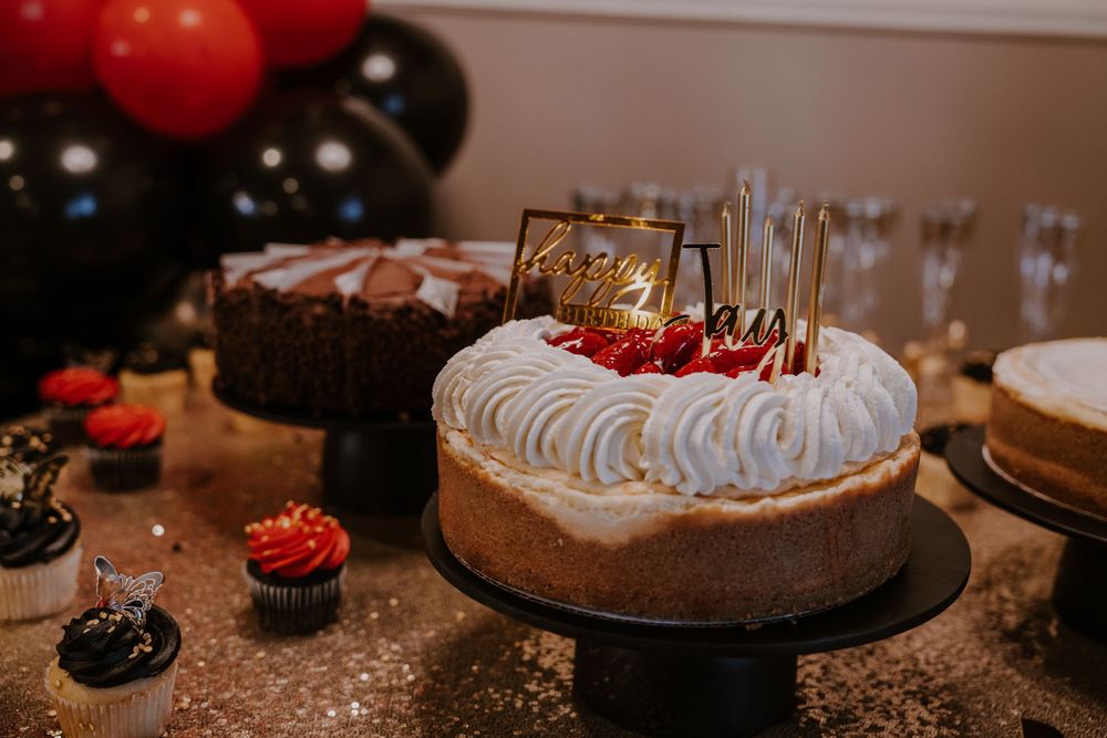 Dessert table featuring chocolate cake and whipped cream topped cakes with red accents and candles.