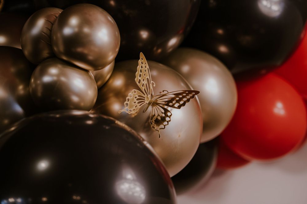 Elegant gold and black balloons with a decorative butterfly accent create a luxurious party atmosphere.